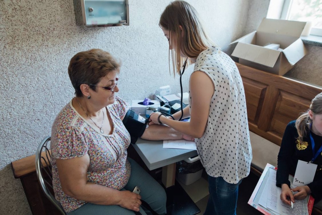 Врач выездной клиники осматривает пациента